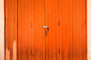Old orange wooden door with a rusty metal lock texture in Thailand.