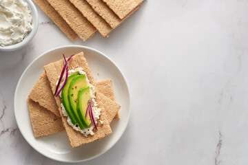 Plate of wheat crispbread with avocado and cream cheese. Top view with copy space.