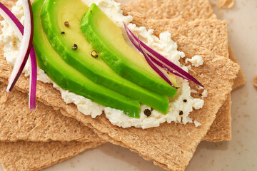 Crispbread with avocado and cream cheese. Top view. Macro shot.