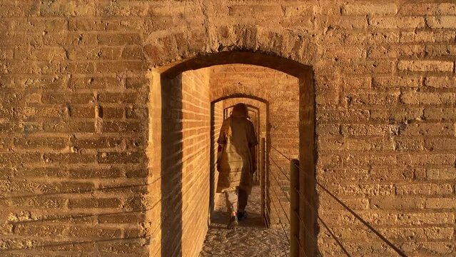 A beautiful Persian girl woman super model is walking through corridor in si-o se pol Esfahan the cultural historical capital of Safavid empire brick architecture design on Zayande roud river in Iran