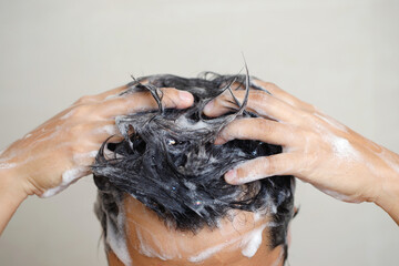 A man is washing his hair with shampoo.