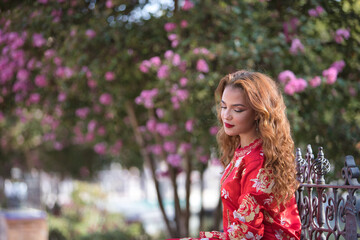 Beautiful young woman in a typical Moroccan red suit, embroidered with gold and silver threads, sitting on a bench with nice curly hair. Concept beauty, ethnicity, typical suits, Marrakech, Arab.