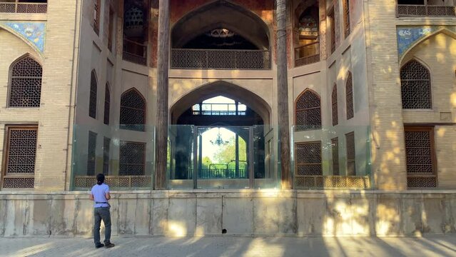 Esfahan historical palace of hasht behesht in the Persian garden with brick walls wooden arch door windows gates pool pavilion in summer wood column old Islamic art traditional building local people