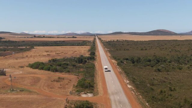 Aerial tracking shot of Van on empty straight road near Margaret River, WA, Australia