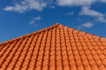 Red tiles panels roof under blue sky.