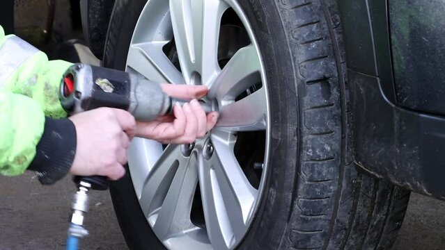 mechanic changing wheel of car with impact wrench
