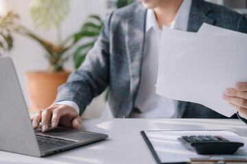 Young Asian businessman working at office with laptop and documents on hand.
