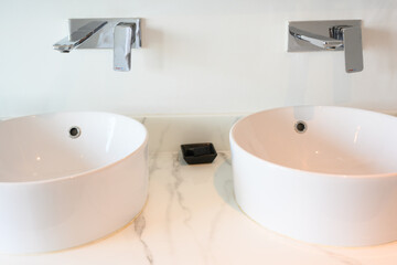 Hygienic wash basin with chrome faucet on bathroom.White washbasin with faucet on marble tile countertop in modern bathroom. Copy space and nobody.