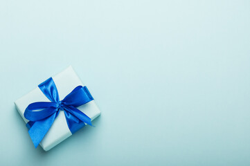Gift box with a satin bow on a blue background. The concept of celebrating father's day, son's day.