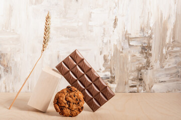 Chocolate chip cookies, chocolate bar and spikelet on a table.