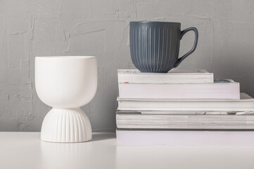 Fototapeta na wymiar Still life with gray cup, white vase and books. Scandinavian interior style.