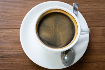 Top view Hot coffee in the white cup  on wooden table background..Cafe drinking menu black coffee at the restaurant with copy space.