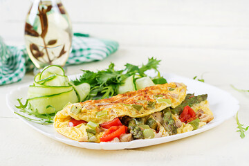 Keto breakfast. Omelette with chicken fillet, tomatoes and asparagus on white wooden table. Italian frittata. Keto, ketogenic lunch.
