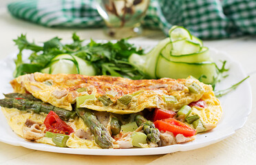 Keto breakfast. Omelette with chicken fillet, tomatoes and asparagus on white wooden table. Italian frittata. Keto, ketogenic lunch.