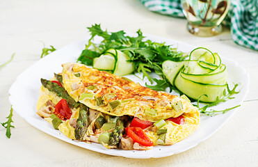 Keto breakfast. Omelette with chicken fillet, tomatoes and asparagus on white wooden table. Italian frittata. Keto, ketogenic lunch.