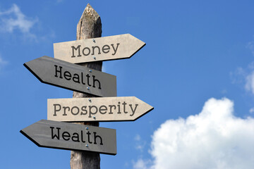 Money, health, prosperity, wealth - wooden signpost with four arrows, sky with clouds