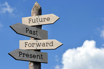 Future, past, forward, present - wooden signpost with four arrows, sky with clouds