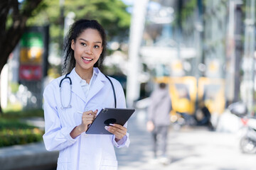 Young female doctor near clinic holding tablet reading news, african-american woman seriously studying information from internet for online consultation with patient, medical health concept