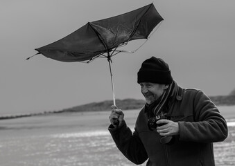 Man with an umbrella on a stormy day, battles against the wind. Captured in monochrome for dramatic...
