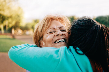 Multiracial senior women hugging each other at city park - Elderly diverse community concept -...