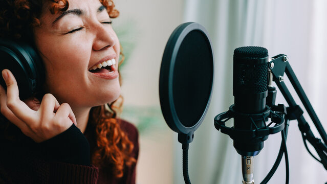 Young musician singer recording music song on microphone at studio - Audio sound performance concept - Focus on woman face