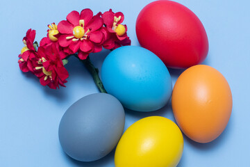 Colorful eggs, symbolizing Easter, on a colorful background and flowers