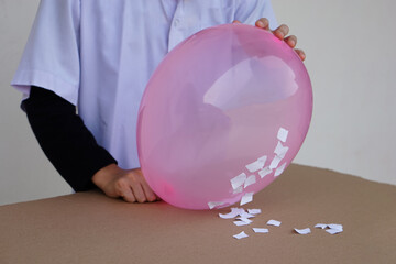 Closeup student do science experiment about static electricty from pink balloon and pieces of...