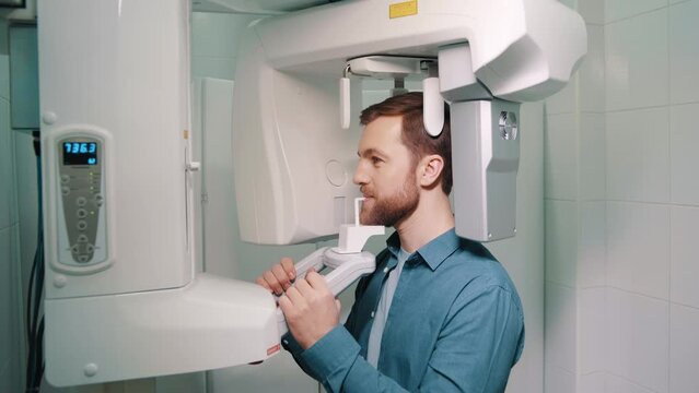 Young male patient undergoing panoramic X-ray investigation of oral cavity using an orthopantomographic machine