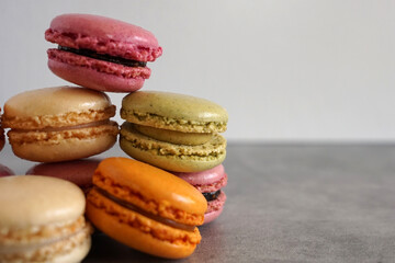 A pile of colorful sweet French macarons against a neutral background.    