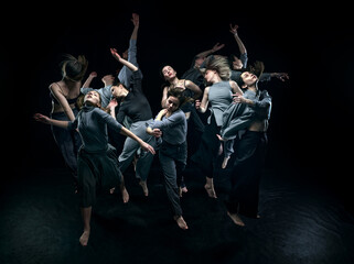 Top view. Dynamic image of young artistic, expressive young people, making contemporary performance, dancing over black studio background. Concept of modern dance, art, movements, creative lifestyle