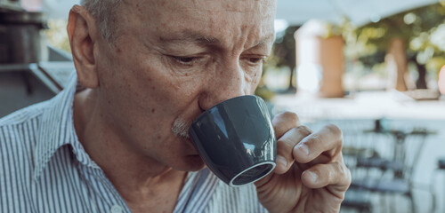 Elderly man drinking espresso coffee at an outdoor cafe