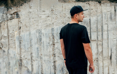 Young guy wearing black blank t-shirt and black cap. Mock-up for print. T-shirt template.