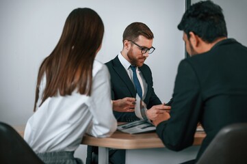 Fototapeta premium Two men and woman are sitting in the office and working