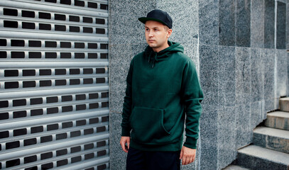 City portrait of handsome guy wearing green (watercolor) blank hoodie or sweatshirt and black...
