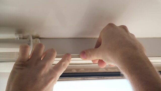 The man wipes the window frame with a degreaser and glues a sealing rubber tape on it for noise insulation, wind protection, weather protection.