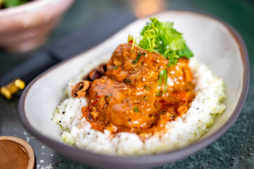 Spicy chicken cooked with curry sauce and rice in bowl
