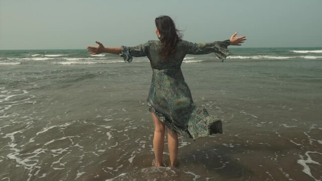 Caucasian Woman Stands With Open Arms, Dress Blows in Ocean Breeze, Slowmo