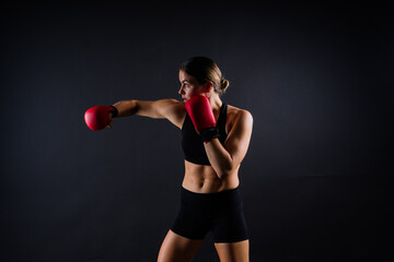 Strong sportswoman in boxing gloves prepared high kick. Isolated on white, red, yellow background