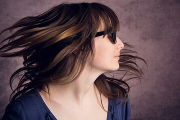 Face of a young model with long brown hair in sunglasses in the studio