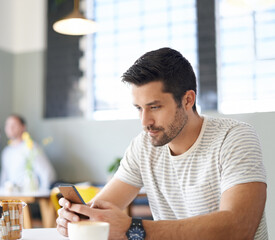 I got us a table. a man using his mobile phone while sitting at a restaurant table.