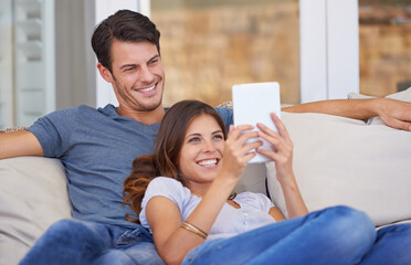 I beat my high score. An affectionate young couple relaxing at home with a digital tablet.