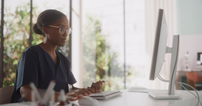 Portrait of a Beautiful Black Female Medical Health Care Professional Working on Computer in Hospital Office. Clinic Head Nurse is Appointing Prescriptions Online, Updating Electronic Health Records