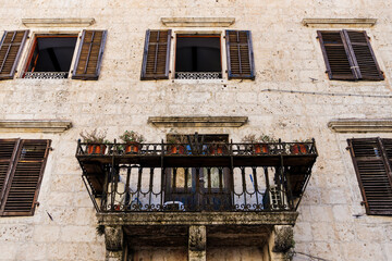 Fototapeta na wymiar Old balconies in the historical part of the city. Wooden shutters and stone walls