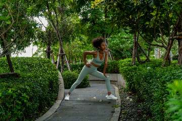 African woman with Afro-textured hair. wearing workout clothes standing exercise in the park