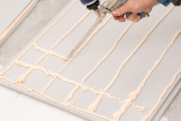Fototapeta na wymiar Foam gun applying gluing foam on styrofoam for warming building. Warming floor with styrofoam concept