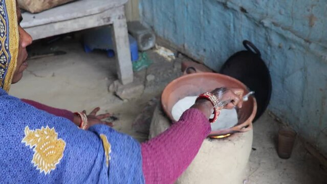 women making rice bread in traditional soil vessels at wood fire from different angle at village