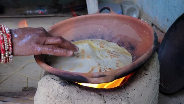 women making rice bread in traditional soil vessels at wood fire from different angle at village