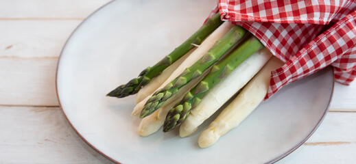 Fresh asparagus on bright ceramic plate. Seasonal vegetables for a healthy nutrion. Background for...