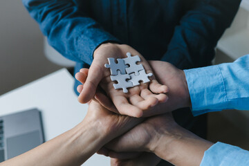 Businessmen hands together jigsaw puzzle in office teamwork conc