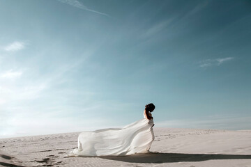 Beautiful Young Pregnant Women, 8 months Pregnant, wearing white lace dress standing in desert sand...
